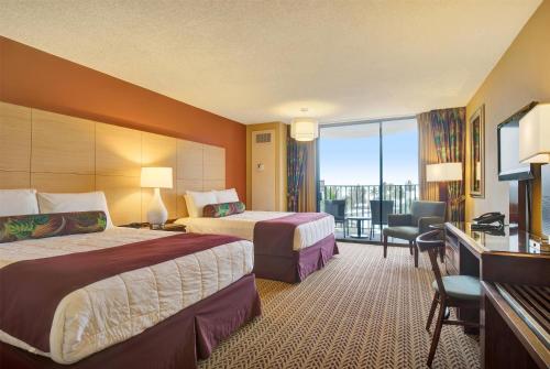 a hotel room with two beds and a balcony at Hilo Hawaiian Hotel, Trademark Collection by Wyndham in Hilo