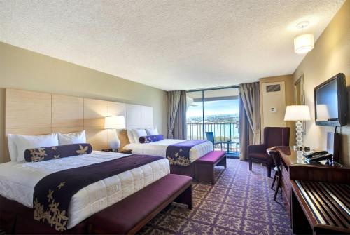 a hotel room with two beds and a balcony at Hilo Hawaiian Hotel, Trademark Collection by Wyndham in Hilo