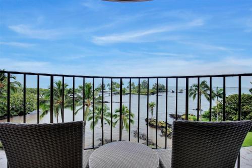 a balcony with two chairs and a view of the ocean at Hilo Hawaiian Hotel, Trademark Collection by Wyndham in Hilo