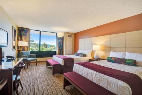 a hotel room with two beds and a window at Hilo Hawaiian Hotel, Trademark Collection by Wyndham in Hilo