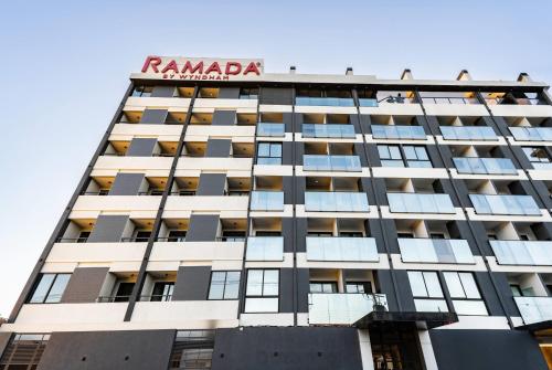 a building with a sign on top of it at Ramada Suites by Wyndham Asuncion Aeropuerto in Asuncion