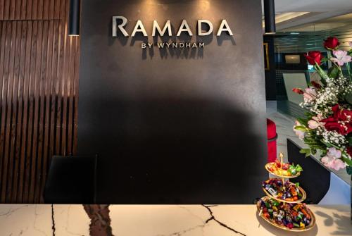 a sign for ramada by wynatown next to a table with flowers at Ramada Suites by Wyndham Asuncion Aeropuerto in Asuncion