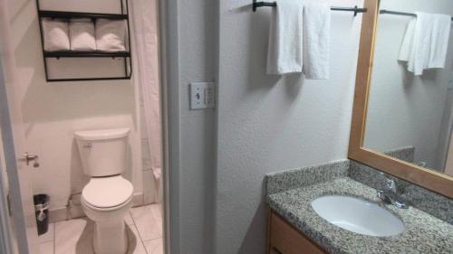 a bathroom with a toilet and a sink and a mirror at Rodeway Inn Yuma Downtown in Yuma