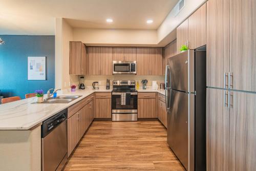 a kitchen with wooden cabinets and a stainless steel refrigerator at The Luxe Lookout Balcony Pool Sleeps 4 in Tempe