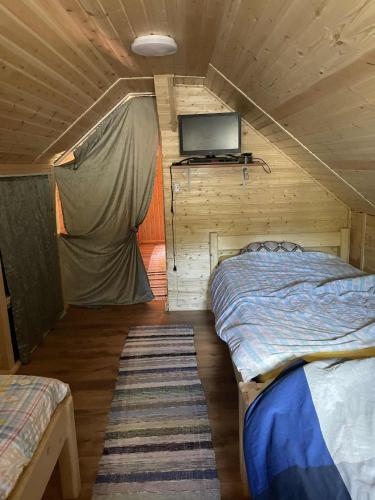 a small bedroom with a bed and a tv in it at Csanodi erdei ház in Gheorgheni