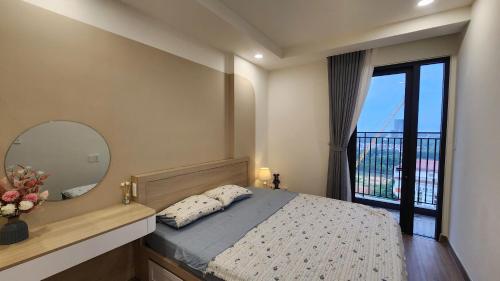 a bedroom with a bed with a mirror and a balcony at Homie's The Glory Apartment in Thu Dau Mot