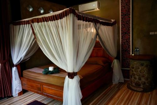 a bedroom with a canopy bed with white curtains at Green Travelodge Bukit Lawang in Bukit Lawang
