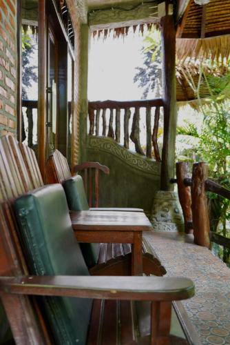 a porch with a chair and a table and a window at Green Travelodge Bukit Lawang in Bukit Lawang