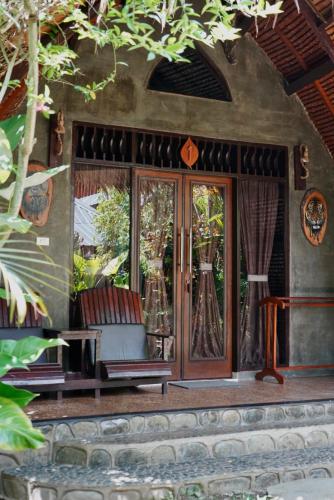 a house with a porch with a chair and glass doors at Green Travelodge Bukit Lawang in Bukit Lawang