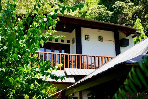 a house with a wooden balcony in the woods at Green Travelodge Bukit Lawang in Bukit Lawang