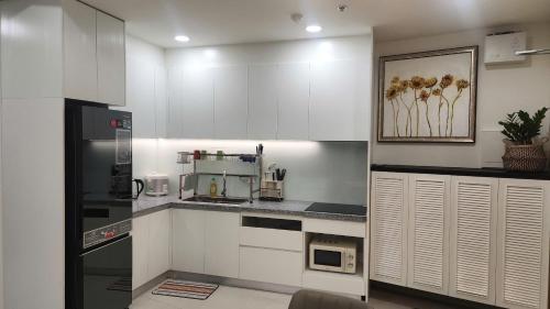 a kitchen with white cabinets and a microwave at Homie's The Glory Apartment in Thu Dau Mot