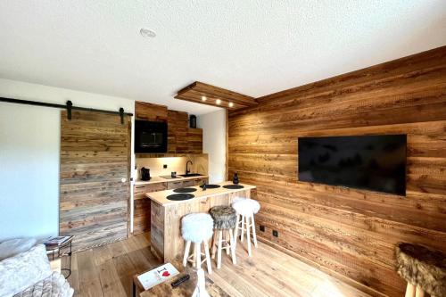 a kitchen with wooden walls and a bar with stools at Les Cimes Blanches in Combloux