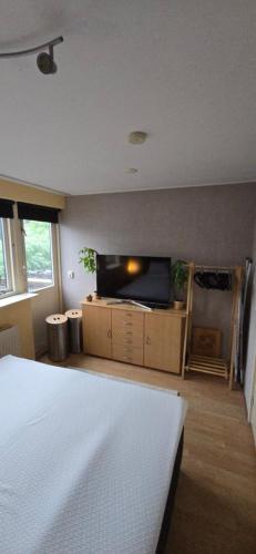Un dormitorio con una cama y un televisor de pantalla plana. en Casa Bron, en Den Helder