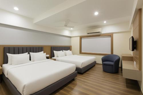 a hotel room with two beds and a tv at The Sky Imperial Welcome, Somnath in Somnath