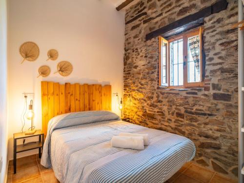 a bedroom with a bed and a stone wall at Casa Crisantemo with sea view and pool in Adra in Las Hoyas del Barranco