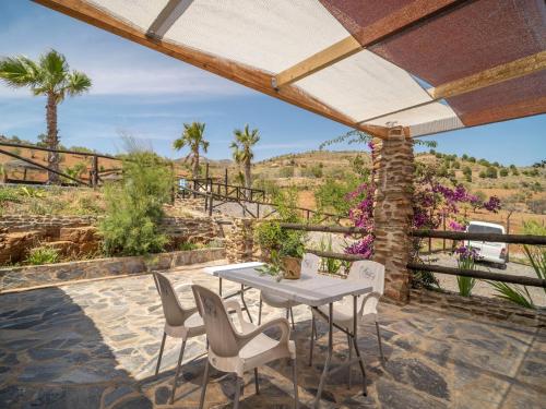 a patio with a table and chairs and palm trees at Casa Crisantemo with sea view and pool in Adra in Las Hoyas del Barranco