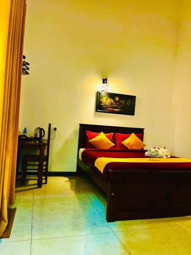 a bedroom with a bed with red and yellow pillows at Queensland Hotel in Nuwara Eliya