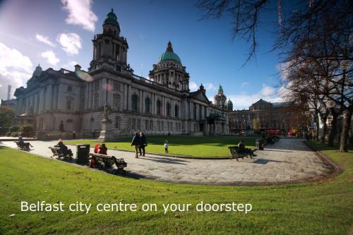 a large building with people sitting on benches in front of it at Harbour View City Centre Apartment in Belfast