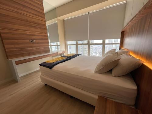 a bedroom with a large bed with a large window at Premium Taman Anggrek Residences in Jakarta