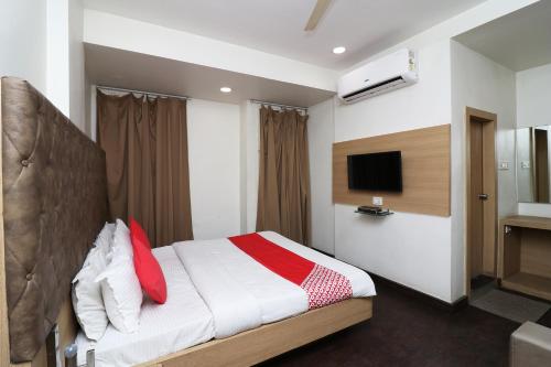 a bedroom with a bed with red pillows and a tv at Hotel O Rajdoot Gaurav in Bhopal