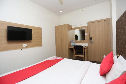 a bedroom with a bed and a tv on the wall at Hotel O Rajdoot Gaurav in Bhopal