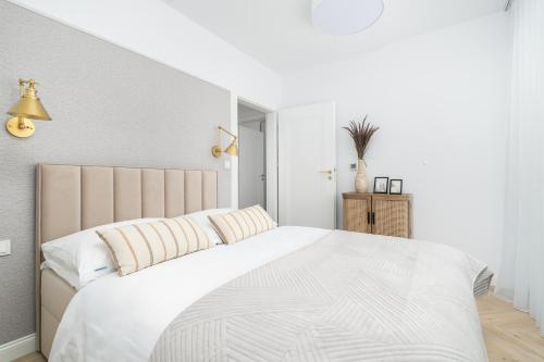 a white bedroom with a large bed with white sheets at Sarbinove City Apartments in Sarbinowo