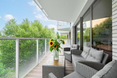 a balcony with chairs and a vase of sunflowers at Sarbinove City Apartments in Sarbinowo