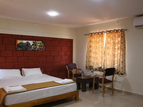 a bedroom with two beds and a table with chairs at Kinara Stay in Kumta