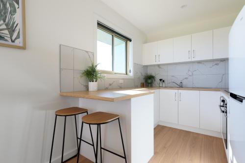 a kitchen with white cabinets and two stools at Waterfront Home with a View and Deck in George Town