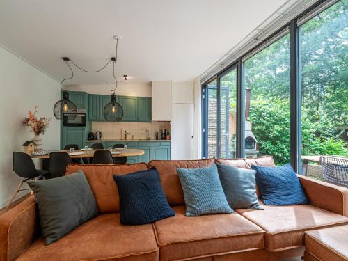 a living room with a brown couch with blue pillows at Tranquil holiday home in the middle of nature in Zelhem