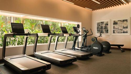 a gym with several tread machines and a window at Mandarin Oriental, Singapore in Singapore