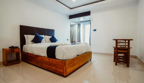 a bedroom with a large bed with blue pillows at Sayora Hotel in Port Blair