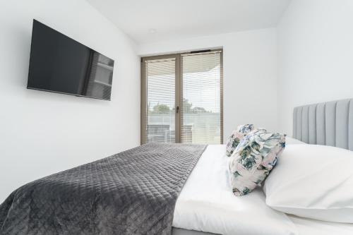 a bedroom with a bed with a flat screen tv at Sarbinove City Apartments in Sarbinowo