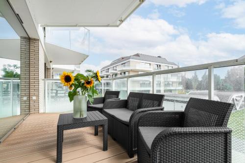 a balcony with chairs and a table with a vase of flowers at Sarbinove City Apartments in Sarbinowo