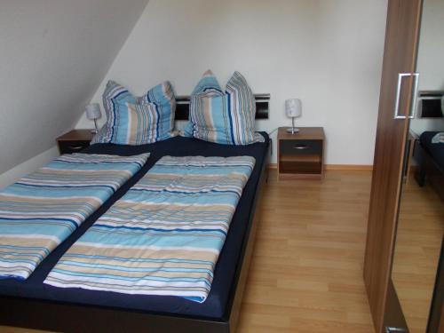Bett mit blauen und weißen Kissen in einem Zimmer in der Unterkunft Ferienwohnung auf Rügen ganz oben in Putgarten