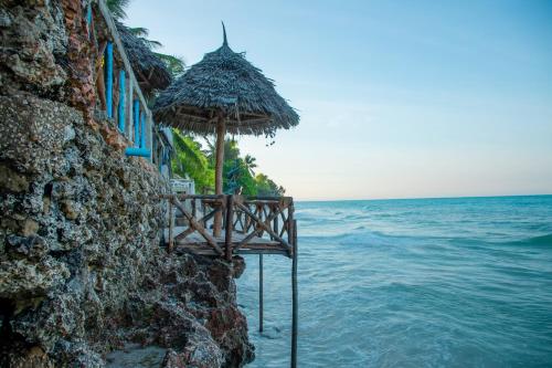 a table with a straw umbrella and the ocean at Art Hotel Zanzibar in Jambiani