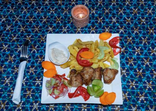 a plate of food with meat and vegetables on a table at Art Hotel Zanzibar in Jambiani