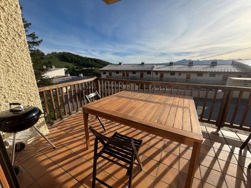 eine Holzterrasse mit einem Tisch und einem Stuhl auf dem Balkon in der Unterkunft Location Appartement Valberg 3 pieces 6 a 7 personnes in Péone