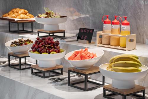a buffet with bowls of fruit and other foods at Platon International Apartment - Lunjiao Metro Station Store in Shunde
