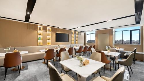 a restaurant with tables and chairs and a flat screen tv at Platon International Apartment - Lunjiao Metro Station Store in Shunde