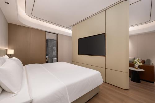a bedroom with a white bed and a flat screen tv at Platon International Apartment - Lunjiao Metro Station Store in Shunde