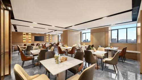 a restaurant with white tables and chairs and windows at Platon International Apartment - Lunjiao Metro Station Store in Shunde