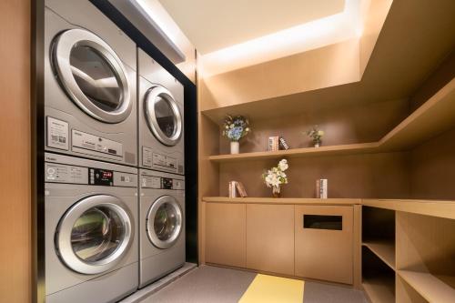 a laundry room with three washer and dryer at Platon International Apartment - Lunjiao Metro Station Store in Shunde