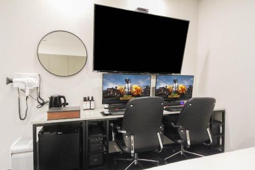 a computer desk with two monitors and two chairs at Arentz Hotel in Anyang