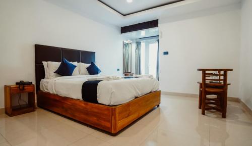 a bedroom with a large bed with blue pillows at Sayora Hotel in Port Blair