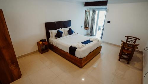 a bedroom with a bed and a chair in it at Sayora Hotel in Port Blair