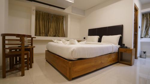 a bedroom with a large bed and a chair at Sayora Hotel in Port Blair