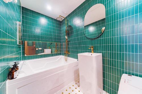 a green tiled bathroom with a tub and a sink at Arentz Hotel in Anyang