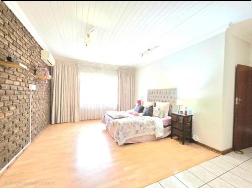 a bedroom with a bed and a brick wall at Flora Gardens guest house in Vanderbijlpark