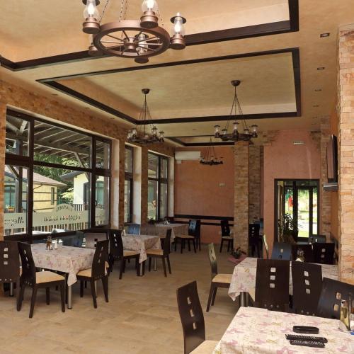 a dining room with tables and chairs and windows at Тодорини Кукли къща за гости in Varshets